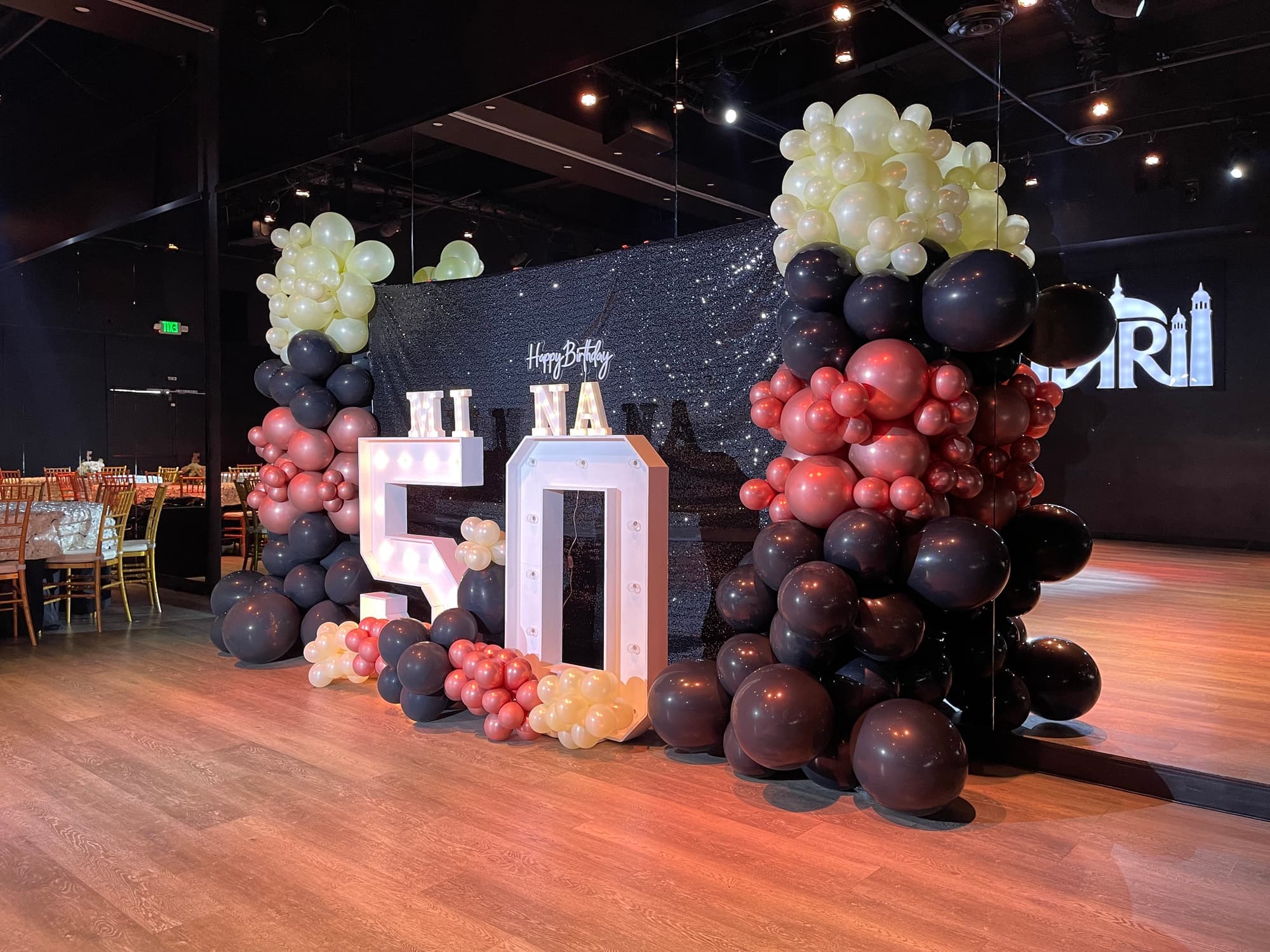 A 50th birthday balloon wall with marquee numbers on the dance floor
