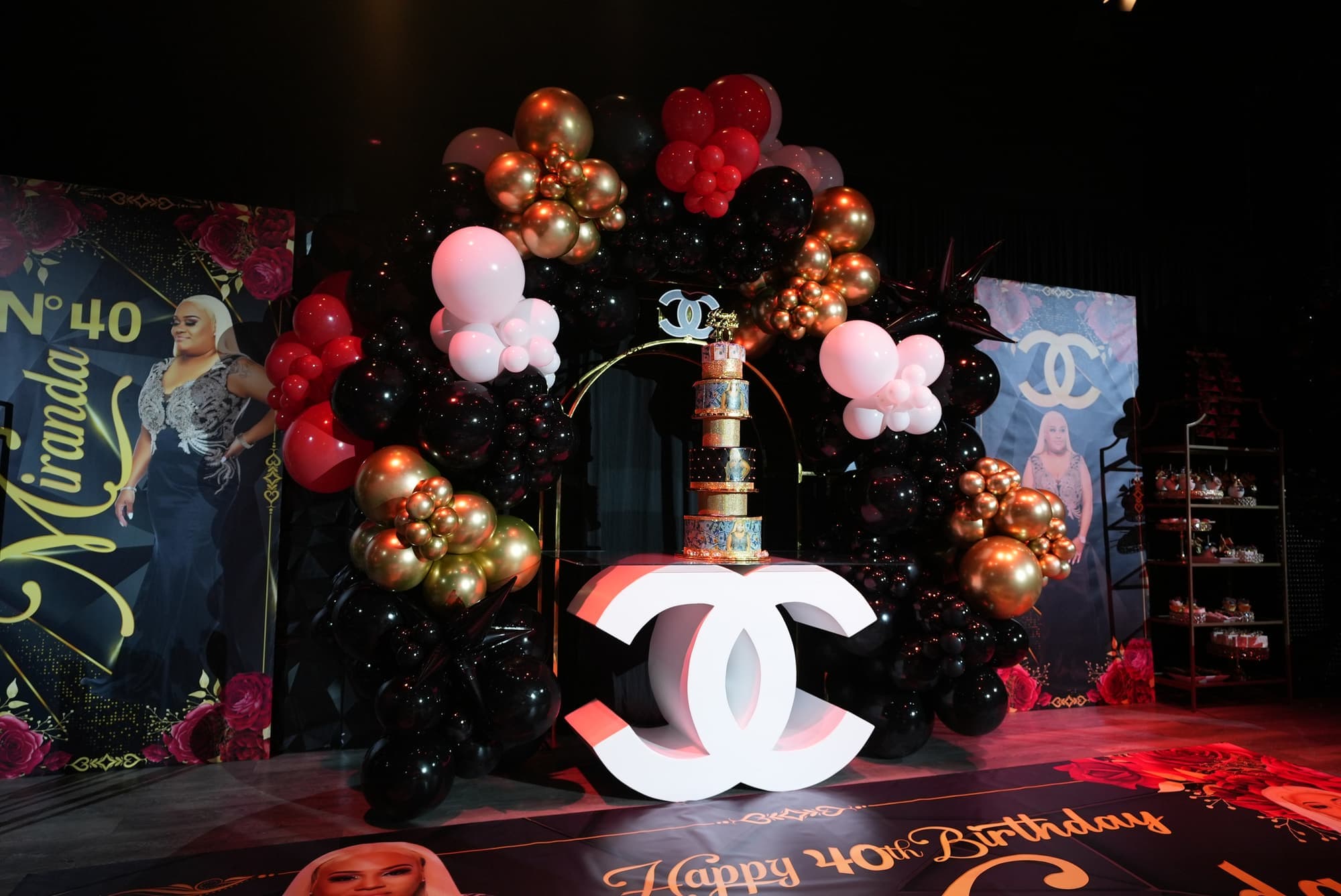 A black, gold and red balloon arch for a 40th birthday cake