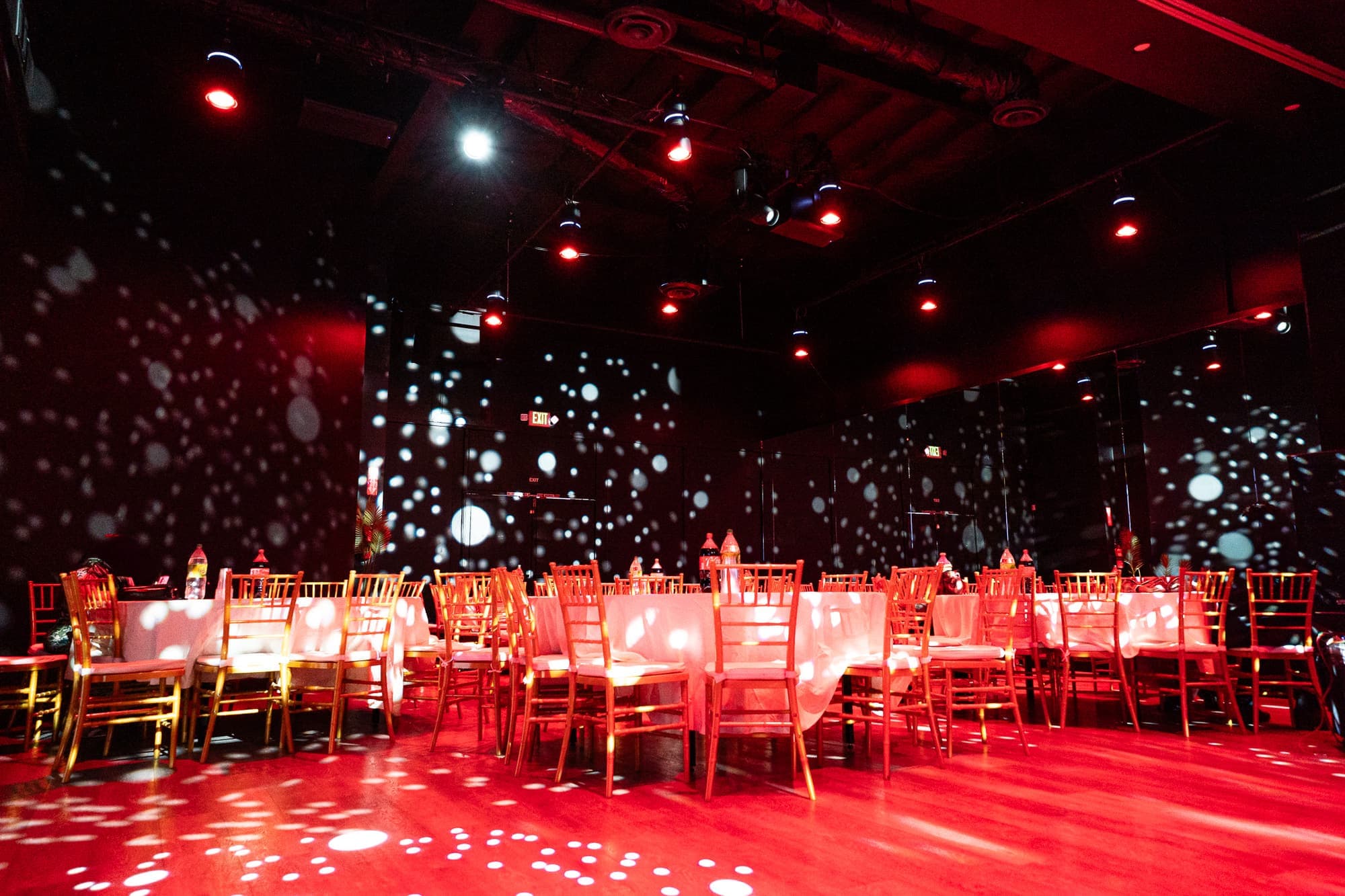A surprise birthday in red light with tables around the dance floor