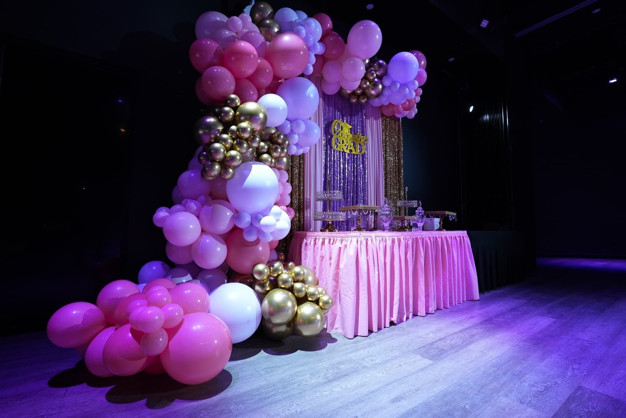 A pink and gold balloon garland over a dessert table