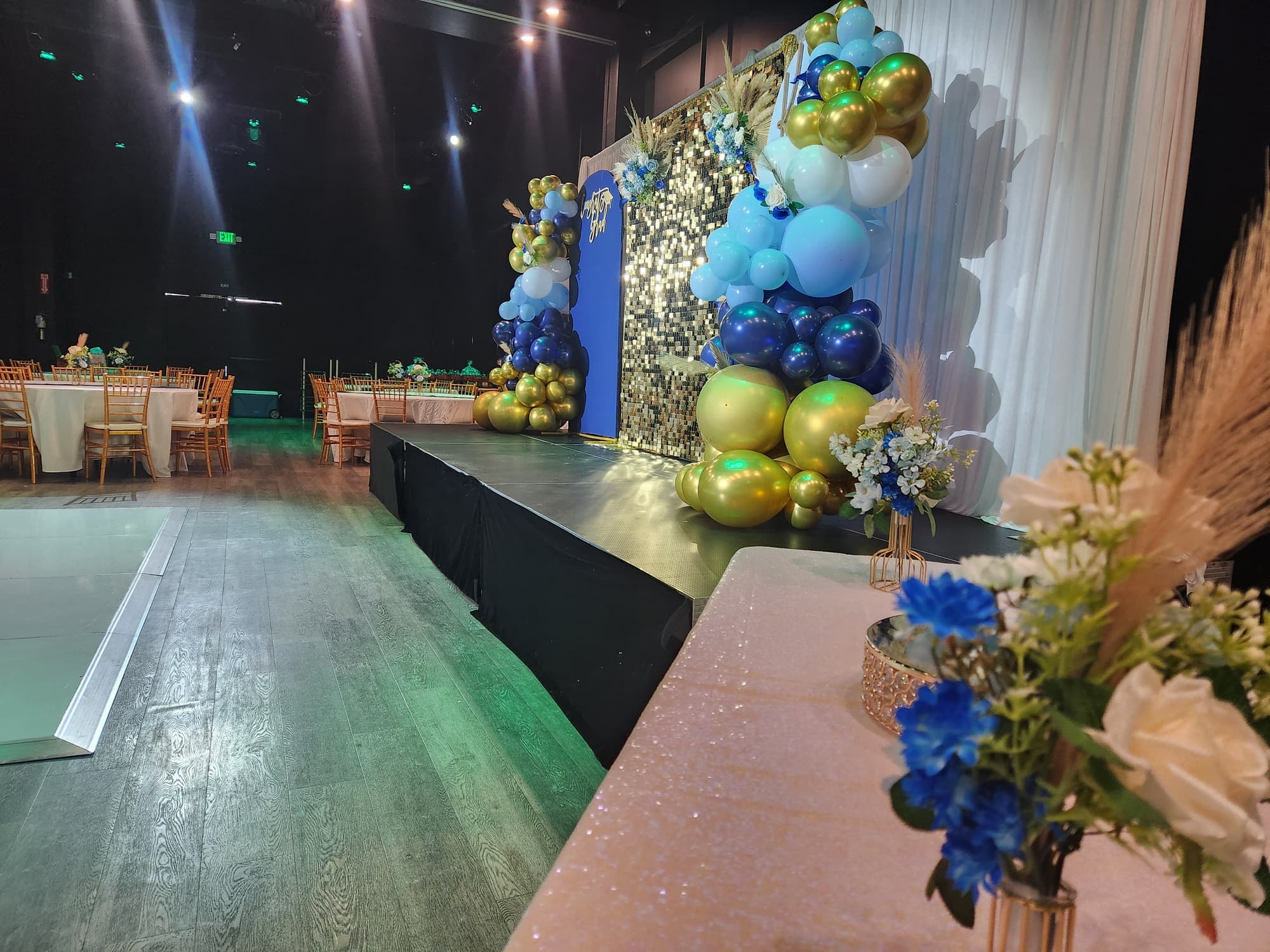 A graduation backdrop with blue and gold balloons on the stage