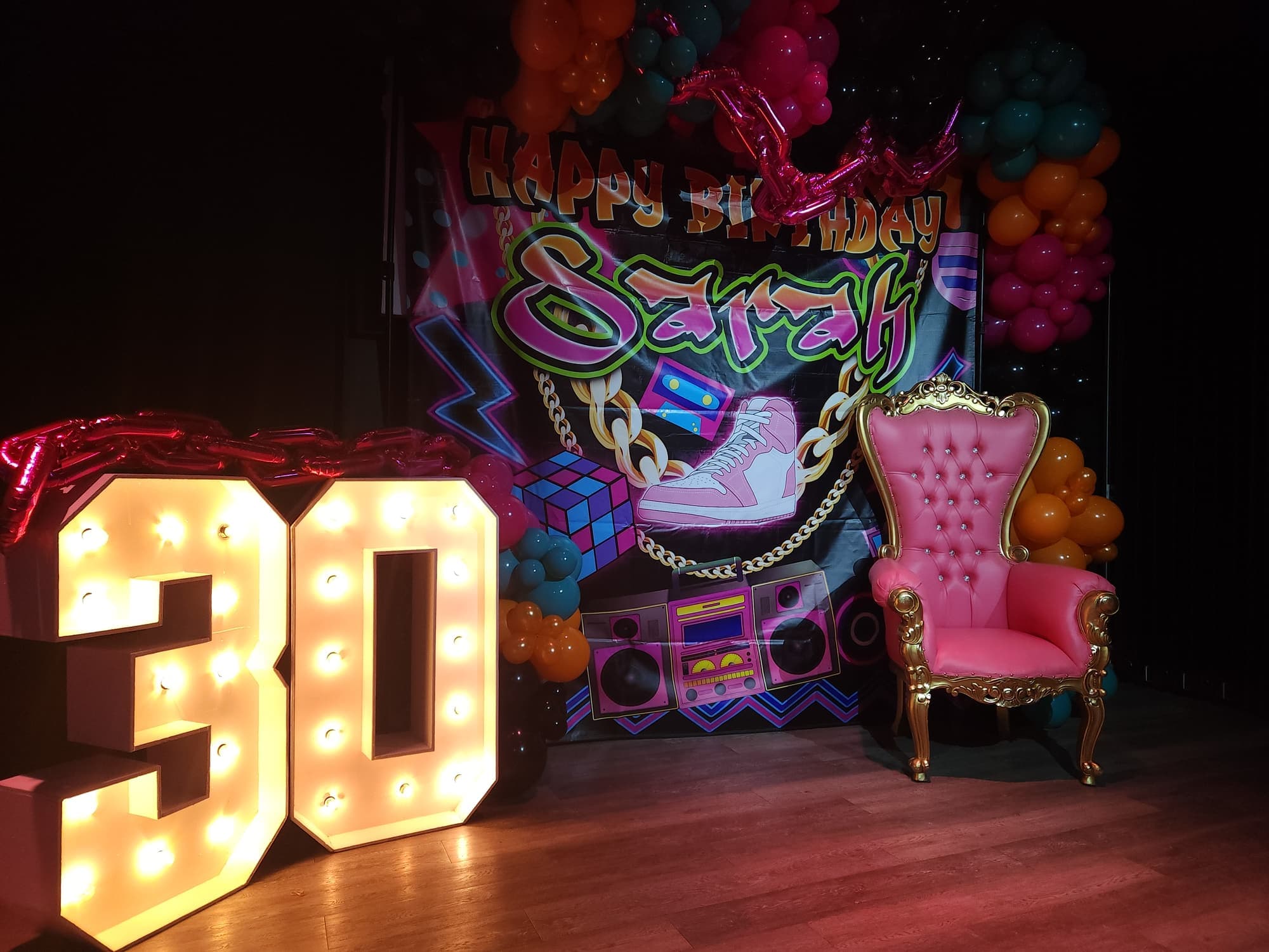 Light-up 30 marquee numbers and a throne chair in front of a themed backdrop