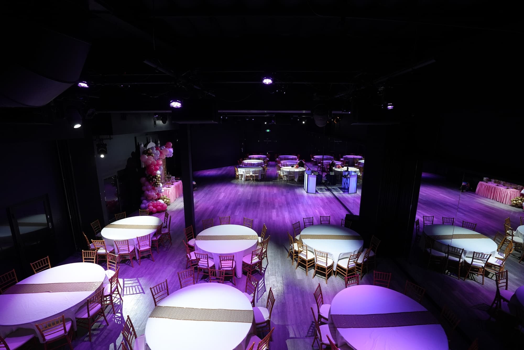 The hall set for a graduation party with round tables in violet light