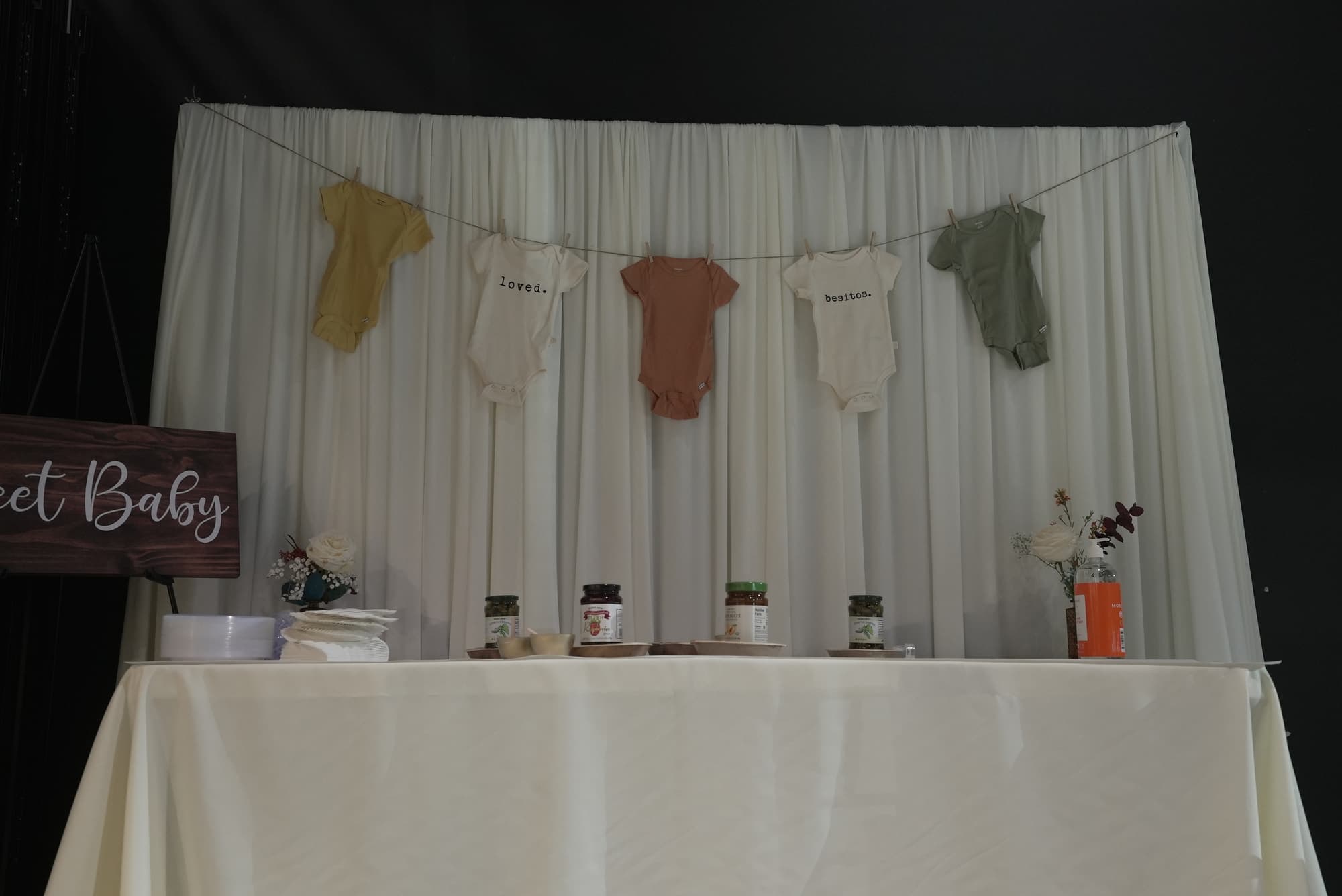 A Sweet Baby backdrop with a line of baby clothes