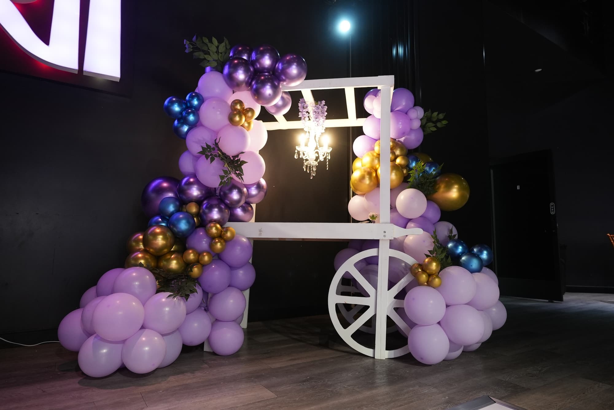 A dessert cart wrapped in purple and gold balloons