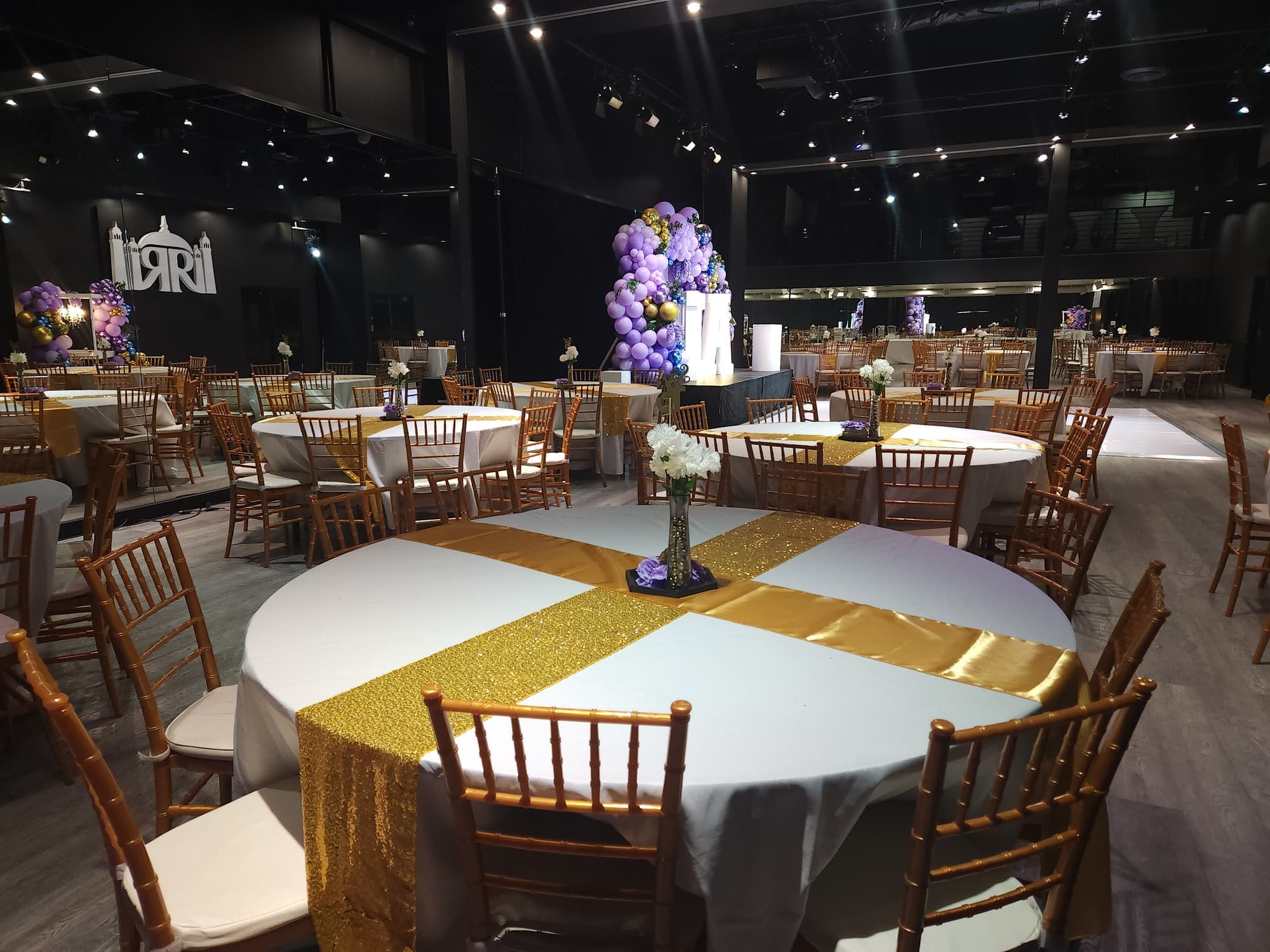 Round tables with gold runners and the balloon arch beyond