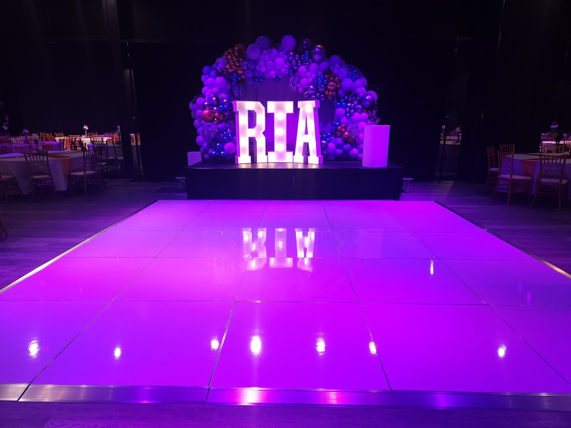 A lit dance floor and a balloon arch with light-up letters for a sweet 16